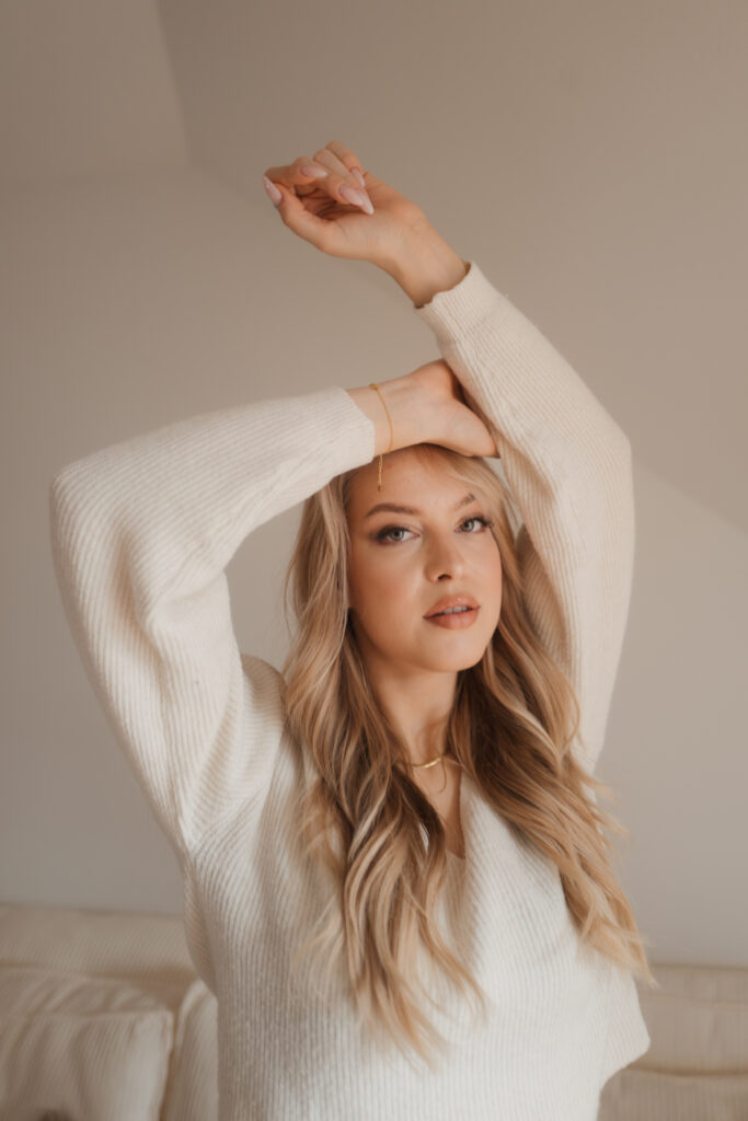 Studio-Portrait einer blonden Frau im hellen Pullover