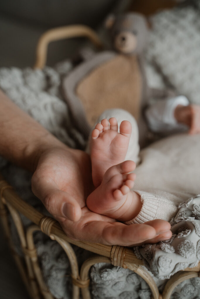 Babyfüße in der Hand des Vaters bei einem Babyshooting