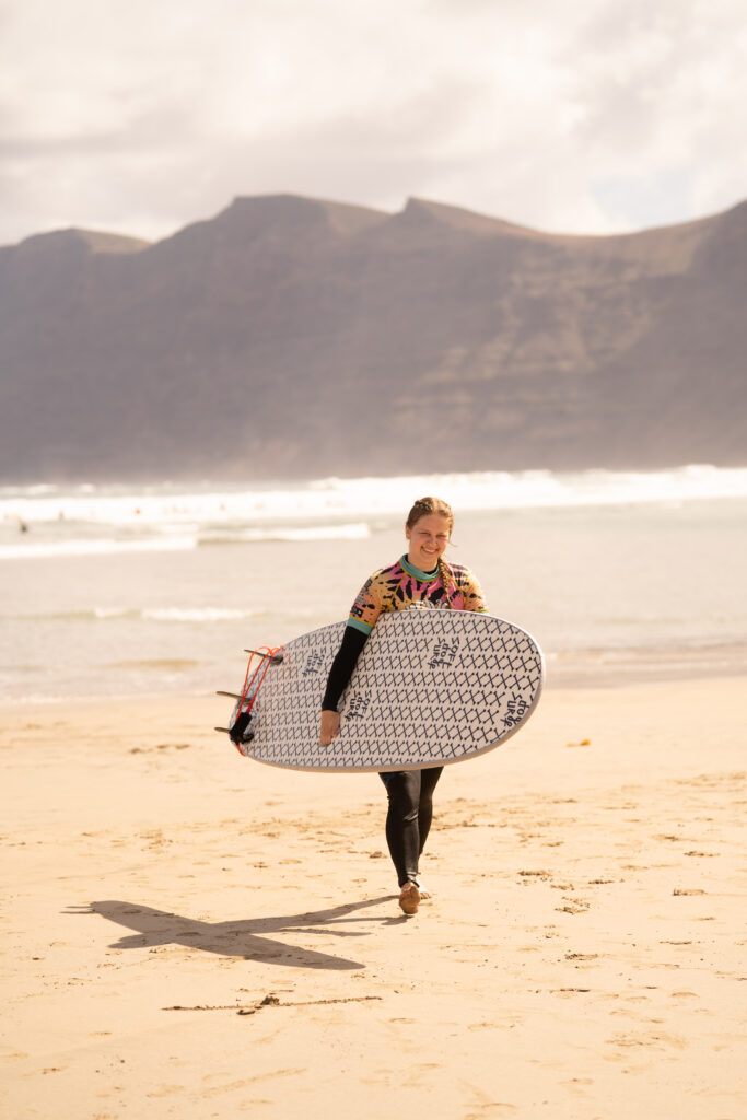 Vicky Diederich mit Surfboard am Strand