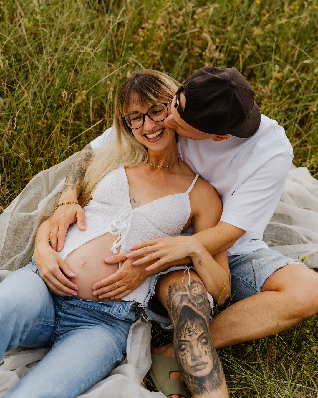Jana und Toby lachen beim Babybauchshooting im hohen Gras